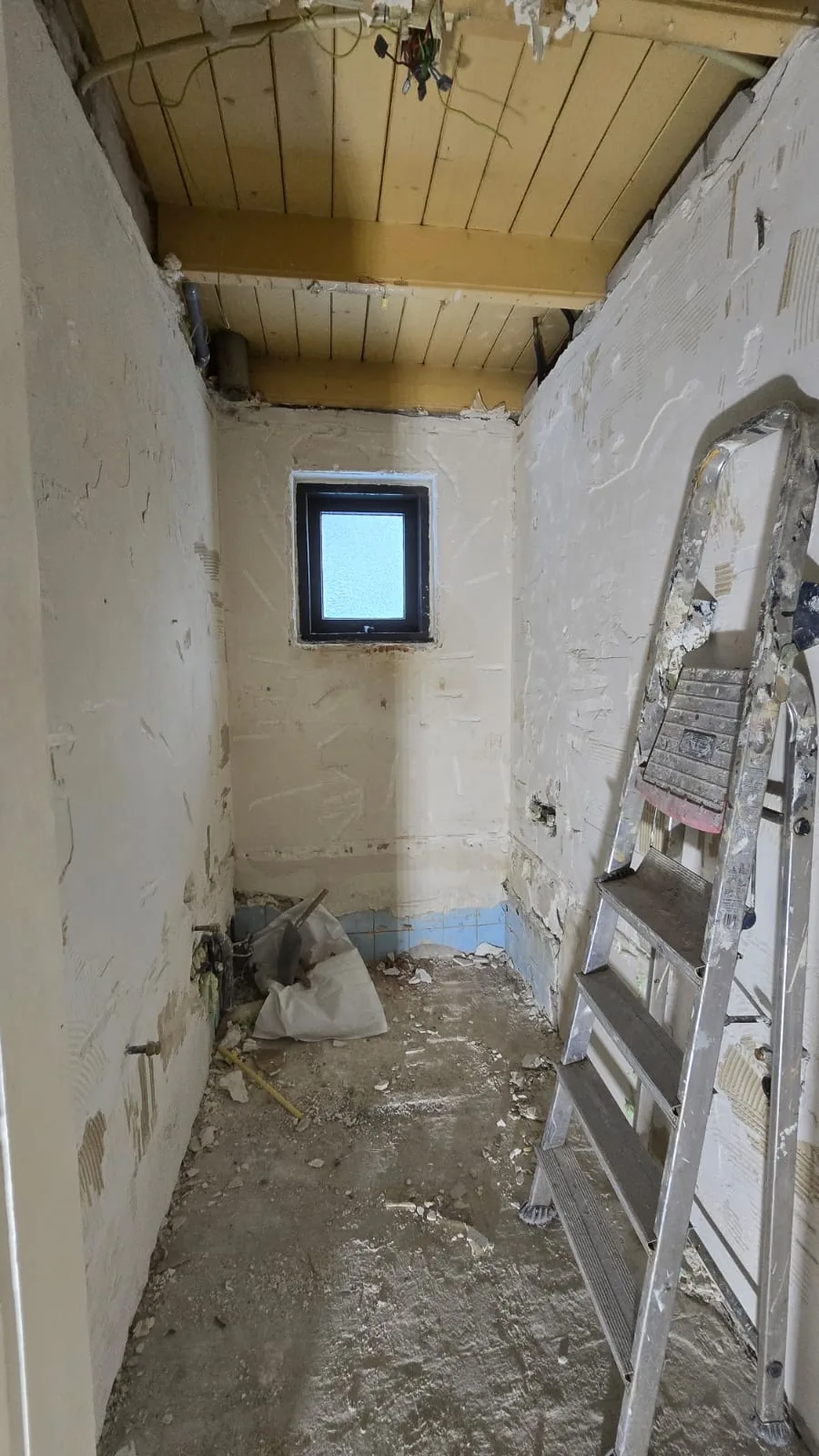 Gestripte badkamer met kale wanden en puin voor de start van de verbouwing
