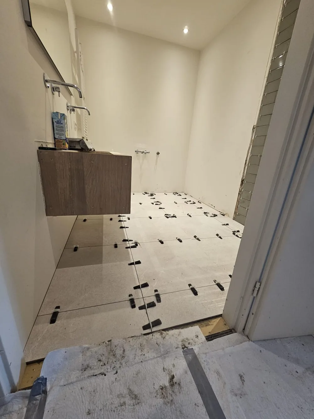 Badkamer tijdens de renovatie met pas gelegde vloertegels en een gemonteerd wastafelmeubel
