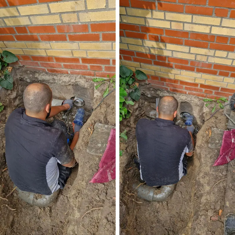Loodgieter sluit een nieuwe pvc-rioolbocht aan bij de gevel in een uitgegraven put