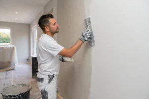 Stukadoor die een wand glad afwerkt ter voorbereiding op strak schilderwerk in een lichte woning