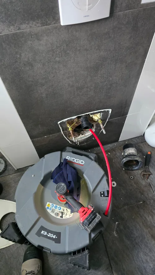 Ontstoppingsmachine bij een verstopte toiletafvoer in een badkamer in Dordrecht